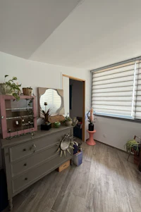 a living room with a dresser and a window